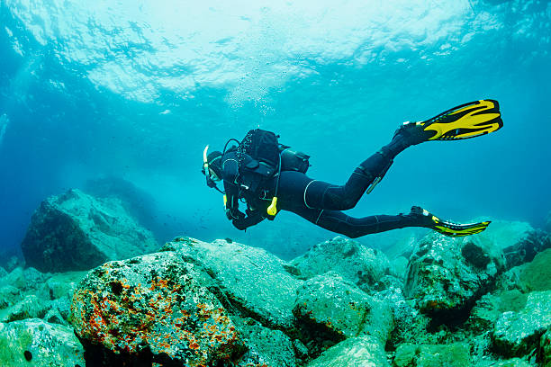 Underwater scene with male scuba diver, enjoy in blue, shallow water.